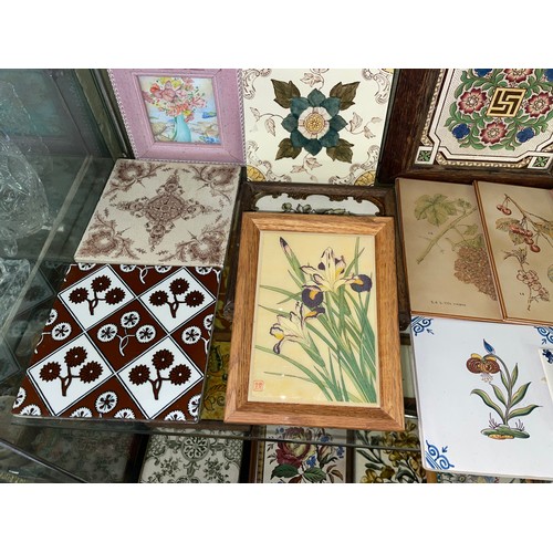 281 - TWO SHELVES OF DECORATIVE CERAMIC TILES AND TILE TRIVETS DECORATED WITH MAINLY FLOWERS AND ANIMALS