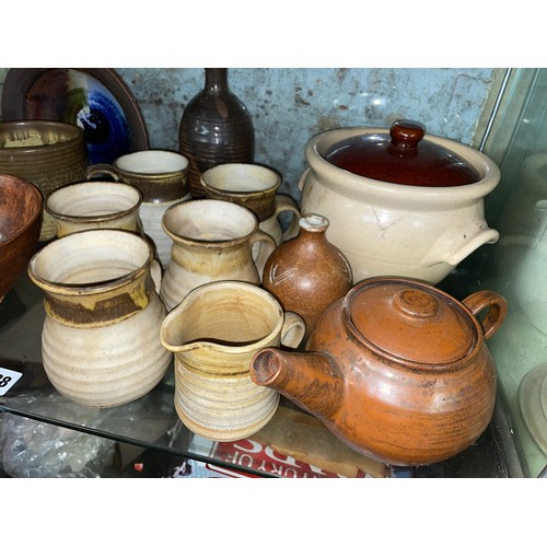 228 - SHELF OF STUDIO POTTERY WARE INCLUDING COFFEE CUPS, TEAPOT, AND LIDDED JARS ETC.