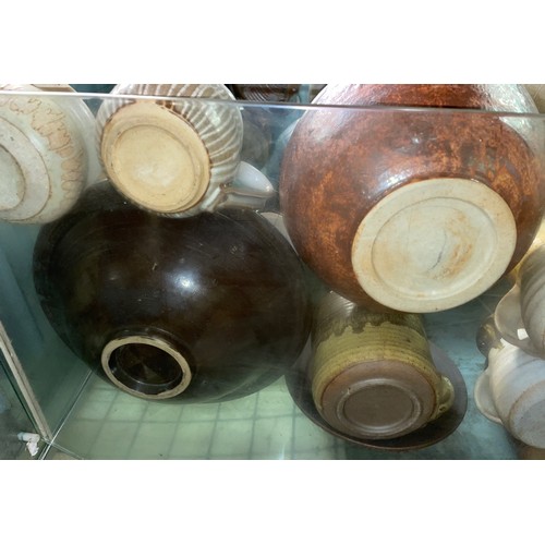 228 - SHELF OF STUDIO POTTERY WARE INCLUDING COFFEE CUPS, TEAPOT, AND LIDDED JARS ETC.