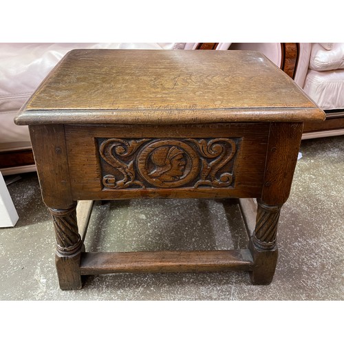 87 - REPRODUCTION OAK HINGED STOOL BOX WITH CARVED ROMAYNE HEAD PANEL