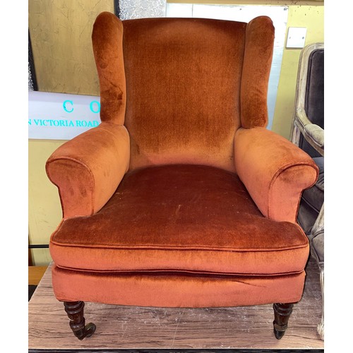 116 - VICTORIAN UPHOLSTERED WING BACK ARMCHAIR ON TURNED FORE LEGS WITH BRASS CUPS AND CASTORS