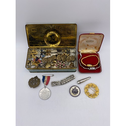 393 - STAINLESS STEEL MARCASITE COCKTAIL WATCH AND VINTAGE TIN OF COSTUME JEWELLERY INC RAF BADGE, ENAMEL ... 