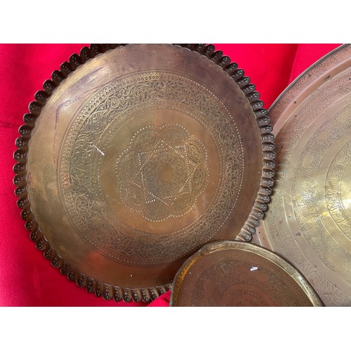 285 - TWO EASTERN BRASS CIRCULAR ENGRAVED TABLE TRAY TOPS, TWO HANDLED TRAY AND SMALLER BRASS ENGRAVED BOW... 