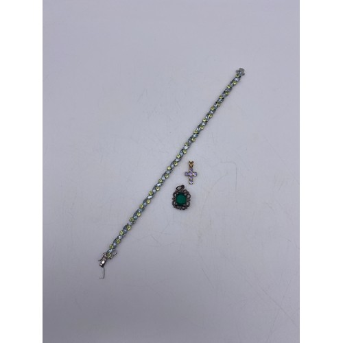 562 - 9K GOLD AND LILAC STONE CROSS, 925 SILVER AND STONE ENCRUSTED TENNIS BRACELET, AND A GREEN STONE CUS... 