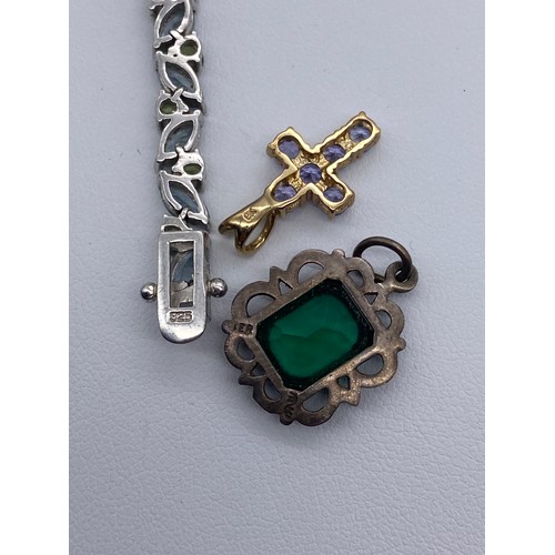 562 - 9K GOLD AND LILAC STONE CROSS, 925 SILVER AND STONE ENCRUSTED TENNIS BRACELET, AND A GREEN STONE CUS... 