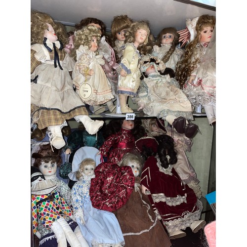 386 - TWO SHELVES OF SMALL TO MEDIUM SIZED PORCELAIN HEADED DRESS DOLLS