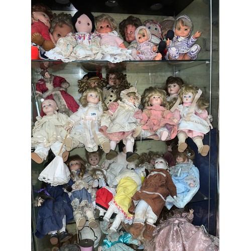 385 - FOUR SHELVES OF VARIOUS PORCELAIN AND PLASTIC DRESS DOLLS