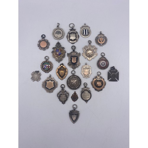 597 - SELECTION OF SILVER AND ENAMEL SHIELD SHAPED AND CIRCULAR MEDALLIONS AND FOBS 6.8OZ APPROX