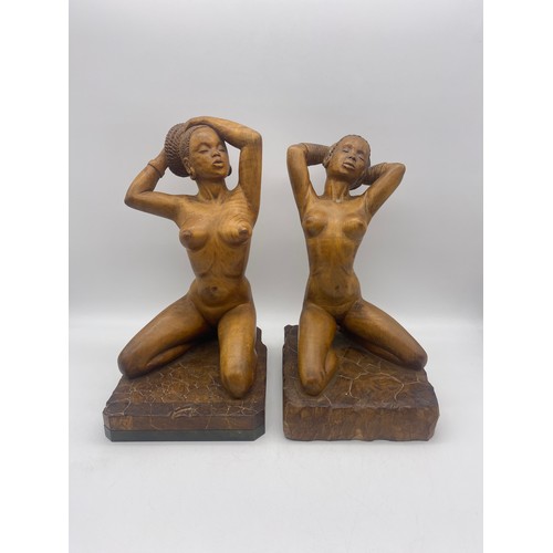 664 - TWO WOODEN CARVINGS OF KNEELING NUDE NUBIAN FEMALES SIGNED GEORGE W DICKER 1960S