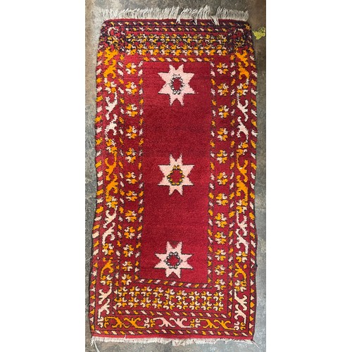 64 - RED GROUND FRINGED CARPET RUNNER 119cm x 61cm