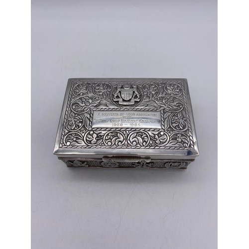 519 - WHITE METAL RECTANGULAR CIGARETTE BOX WITH REPOUSSE DECORATION AND ARMORIAL CREST PRESENTATION INSCR... 