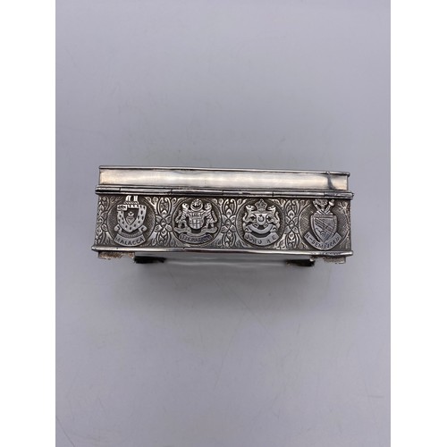 519 - WHITE METAL RECTANGULAR CIGARETTE BOX WITH REPOUSSE DECORATION AND ARMORIAL CREST PRESENTATION INSCR... 