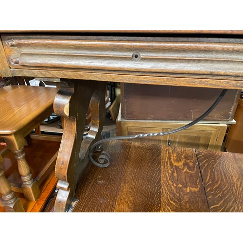 148 - CONTINENTAL OAK LEATHER TOPPED AND WROUGHT IRON WORK TABLE FITTED WITH TWO LINENFOLD DRAWERS