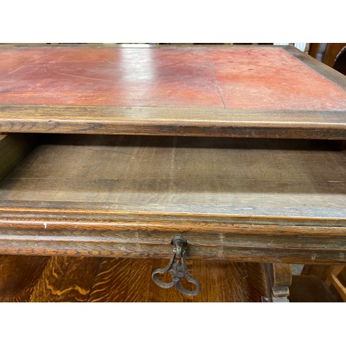 148 - CONTINENTAL OAK LEATHER TOPPED AND WROUGHT IRON WORK TABLE FITTED WITH TWO LINENFOLD DRAWERS