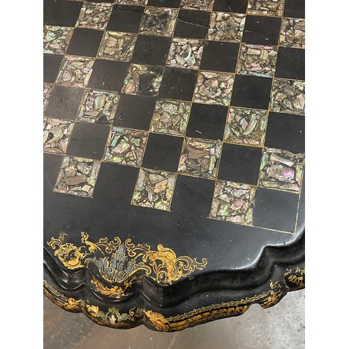 110A - BLACK LACQUERED PAPIER MACHE TILT TOP CHESS TABLE WITH ABALONE BOARD AND GILT BORDER A/F