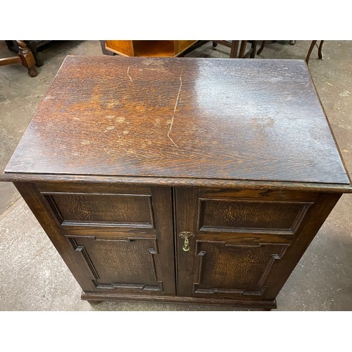 85 - OAK GEOMETRIC PANELLED TWO DOOR CUPBOARD ON BUN FEET