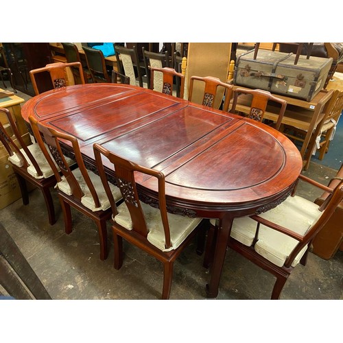 74 - CHINESE INFLUENCE CARVED ROSEWOOD EFFECT EXTENDING DINING TABLE AND EIGHT CHAIRS WITH LOOSE CUSHIONS