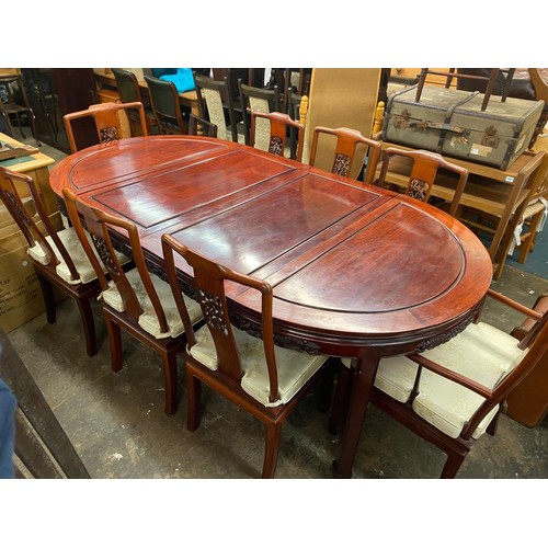 74 - CHINESE INFLUENCE CARVED ROSEWOOD EFFECT EXTENDING DINING TABLE AND EIGHT CHAIRS WITH LOOSE CUSHIONS