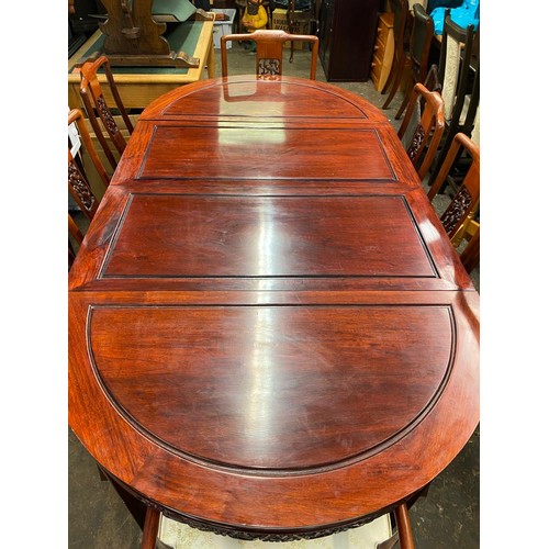 74 - CHINESE INFLUENCE CARVED ROSEWOOD EFFECT EXTENDING DINING TABLE AND EIGHT CHAIRS WITH LOOSE CUSHIONS