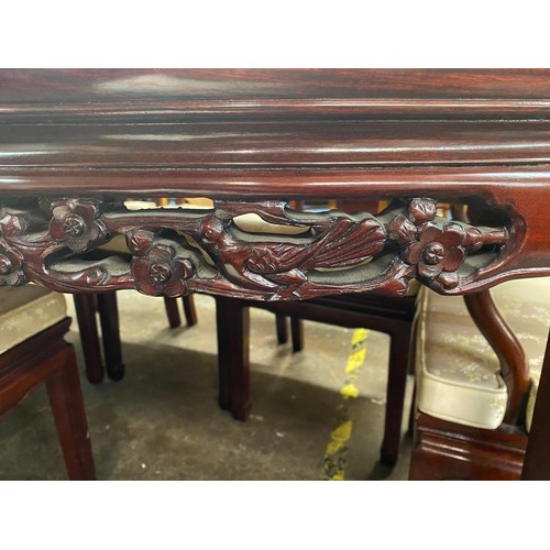 74 - CHINESE INFLUENCE CARVED ROSEWOOD EFFECT EXTENDING DINING TABLE AND EIGHT CHAIRS WITH LOOSE CUSHIONS