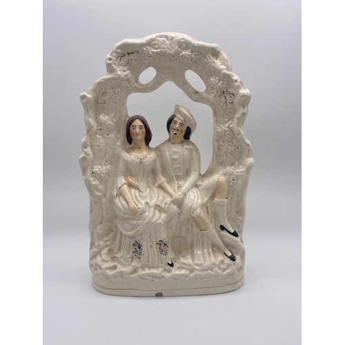 554 - STAFFORDSHIRE FLAT BACK FIGURE OF A COUPLE UNDER ARCH AND ONE SMALLER FIGURE 34.5CM H AND 24.5CM H