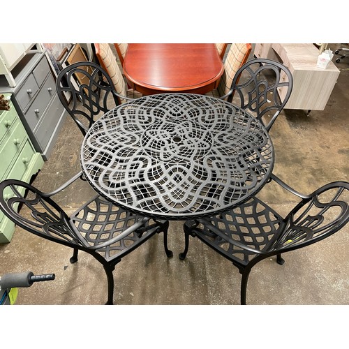 76 - BLACKENED CAST METAL CIRCULAR PATIO TABLE AND FOUR ARMCHAIRS