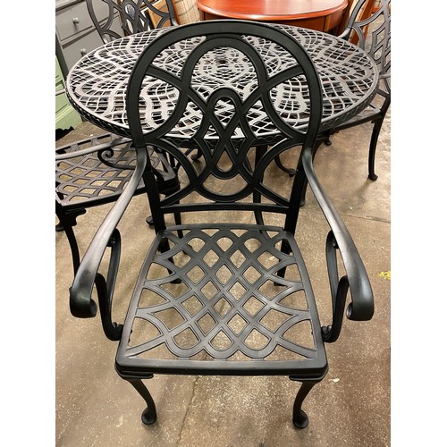 76 - BLACKENED CAST METAL CIRCULAR PATIO TABLE AND FOUR ARMCHAIRS