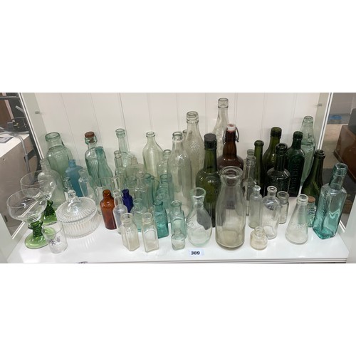 389 - QTY OF CLEAR GREEN AND BLUE GLASS CHEMIST BOTTLES AND JARS, SODA BOTTLES, AND ADVERTISING WARES