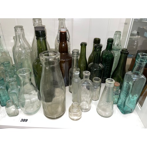 389 - QTY OF CLEAR GREEN AND BLUE GLASS CHEMIST BOTTLES AND JARS, SODA BOTTLES, AND ADVERTISING WARES