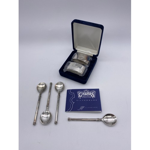 428 - BOXED PAIR OF SILVER CARRS SERVIETTE RINGS AND PLATED TEASPOONS