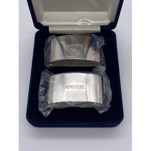 428 - BOXED PAIR OF SILVER CARRS SERVIETTE RINGS AND PLATED TEASPOONS