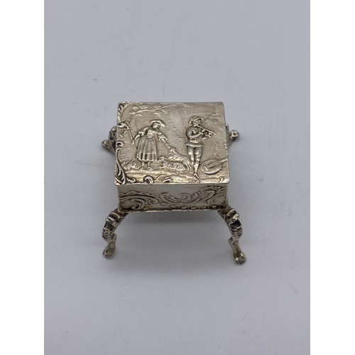 462 - IMPORTED LONDON SILVER MINIATURE RAISED SQUARE SECTION TRINKET BOX HINGE A/F DECORATED WITH COURTING... 