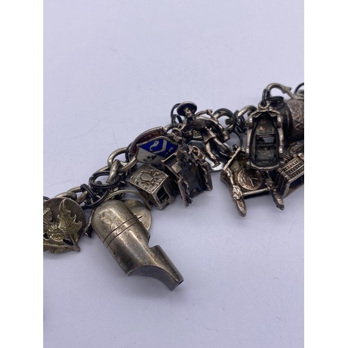 459 - SILVER CHARM BRACELET WITH NUMEROUS NOVELTY CHARMS WISHING WELL, WINDMILL, BLACKPOOL TOWER, SCISSORS... 