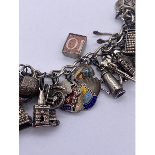 459 - SILVER CHARM BRACELET WITH NUMEROUS NOVELTY CHARMS WISHING WELL, WINDMILL, BLACKPOOL TOWER, SCISSORS... 