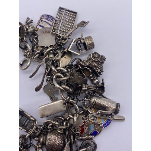 459 - SILVER CHARM BRACELET WITH NUMEROUS NOVELTY CHARMS WISHING WELL, WINDMILL, BLACKPOOL TOWER, SCISSORS... 