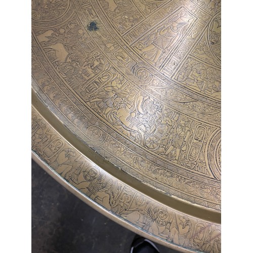 223 - EGYPTIAN ENGRAVED BRASS DISH TOP TABLE ON FOLDING EBONISED AND BONE STAND