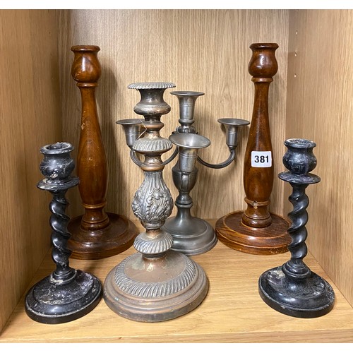 381 - PIGEON HOLE OF PAIRS OF EBONISED AND WOODEN TURNED CANDLE STICKS AND METAL CANDLEARBRUM