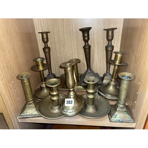 382 - PIGEONHOLE OF BRASS CHAMBER STICKS AND PAIRS OF BRASS CYLINDRICAL AND TAPERED CANDLE STICKS