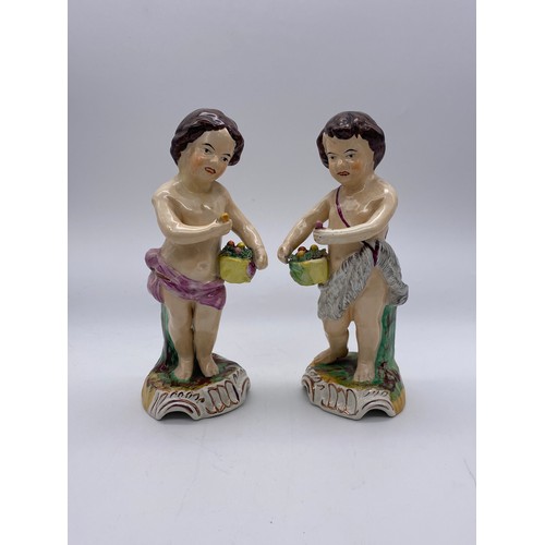 791 - PAIR OF 19TH CENTURY STAFFORDSHIRE PUTTO FIGURES CARRYING BASKETS OF FLOWERS HEIGHT 23CM APPROX