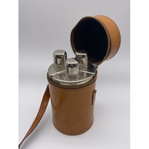 806 - LEATHER CYLINDRICAL THREE GLASS SPIRIT FLASK AND A LEATHER CASED TRAVELLING TRIPLE FLASK WITH ENAMEL... 