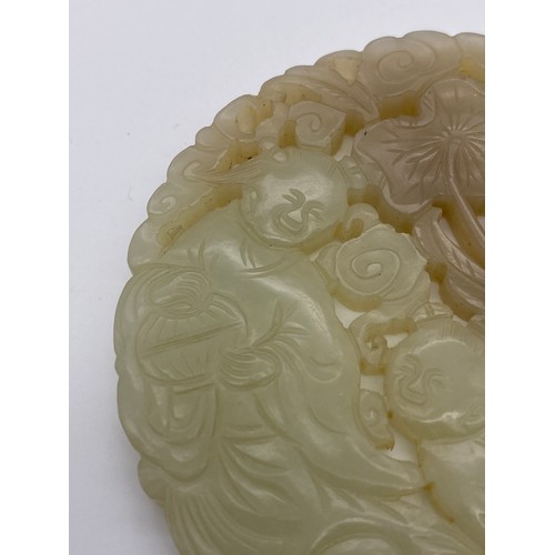 765 - 18TH CENTURY PALE CELADON JADE ROUNDEL PLAQUE DECORATED WITH FIGURES AMIDST FOLIAGE