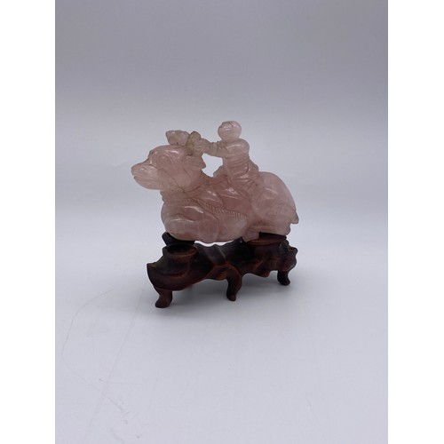 774 - CHINESE ROSE QUARTZ CARVING OF A BOY ASTRIDE A WATER BUFFALO ON STAND A/F