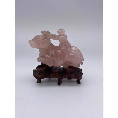 774 - CHINESE ROSE QUARTZ CARVING OF A BOY ASTRIDE A WATER BUFFALO ON STAND A/F