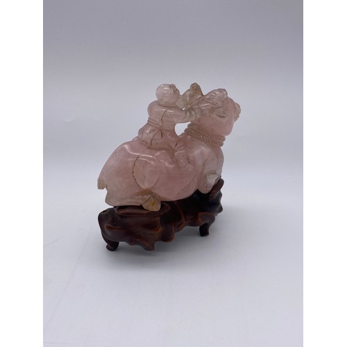 774 - CHINESE ROSE QUARTZ CARVING OF A BOY ASTRIDE A WATER BUFFALO ON STAND A/F