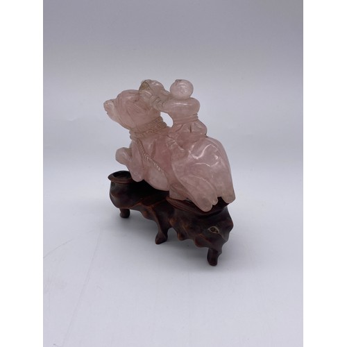 774 - CHINESE ROSE QUARTZ CARVING OF A BOY ASTRIDE A WATER BUFFALO ON STAND A/F