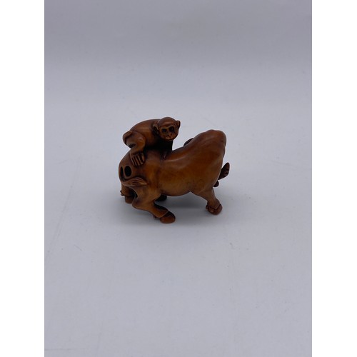 779 - JAPANESE BOX WOOD NETSUKE OF A WATER BUFFALO WITH A MONKEY ON ITS BACK