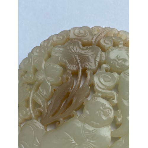 765 - 18TH CENTURY PALE CELADON JADE ROUNDEL PLAQUE DECORATED WITH FIGURES AMIDST FOLIAGE