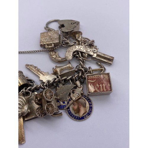 530 - SILVER CHARM BRACELET WITH HEART PADLOCK AND VARIOUS NOVELTY CHARMS 93G APPROX