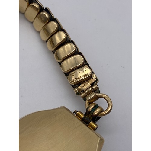 629 - LADIES 9CT GOLD CASED VISIBLE WRIST WATCH ON ELASTICATED GOLD CORE BRACELET STRAP