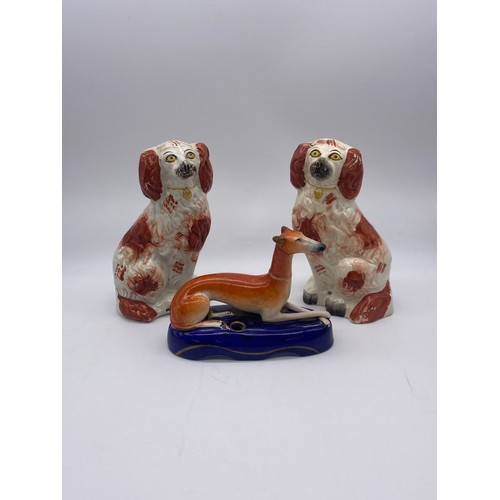 252 - STAFFORDSHIRE RECUMBENT WHIPPET INKWELL A/F AND PAIR OF SEATED SPANIELS